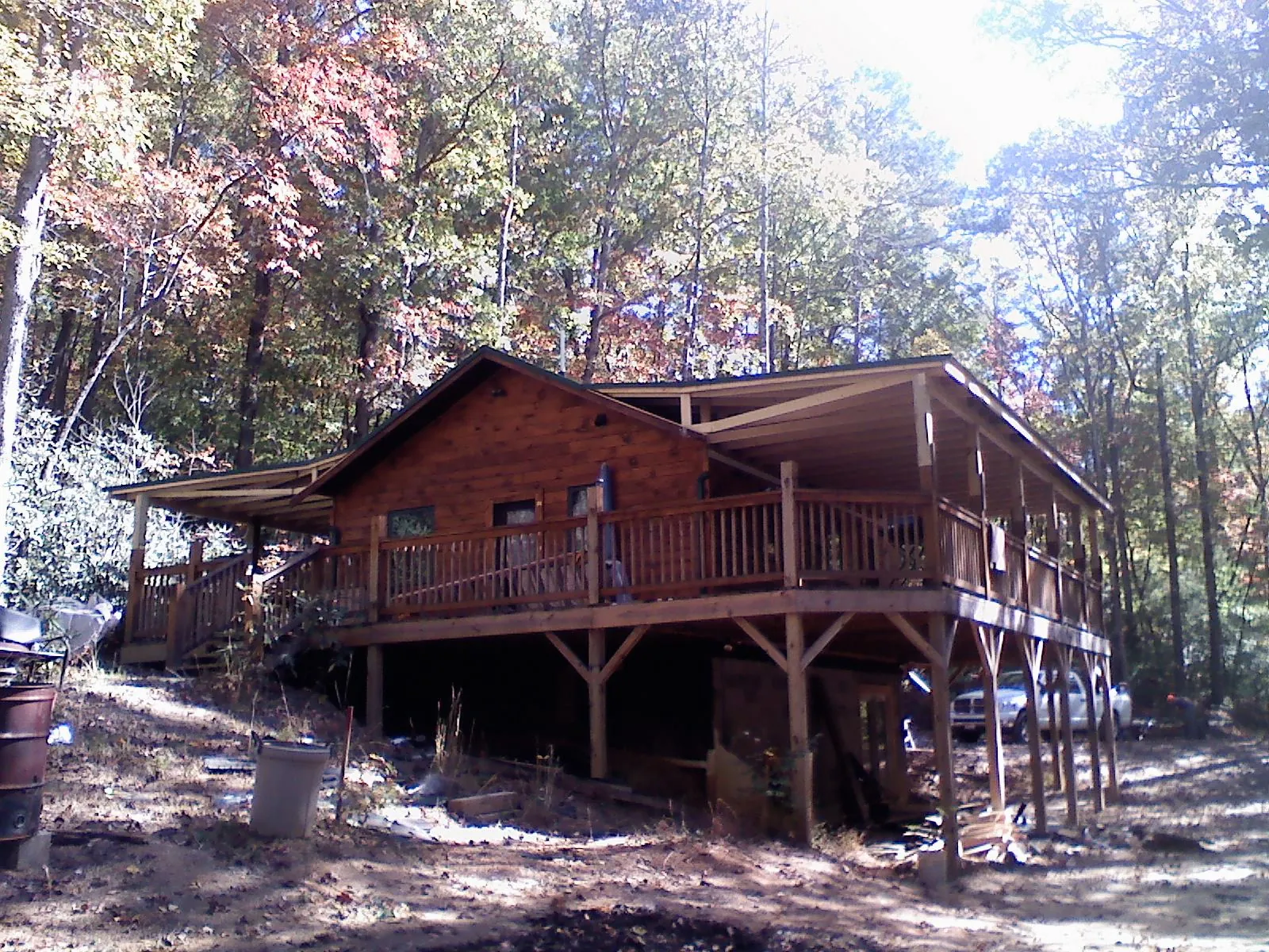 Log cabin with a wraparound porch and metal roof in the fall in Butler